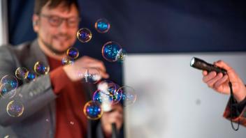 An Seifenblasen demonstriert Prof. Dr. Boris Hage die spektrale Aufspaltung von Licht, die dann in bunten Farben erscheinen.