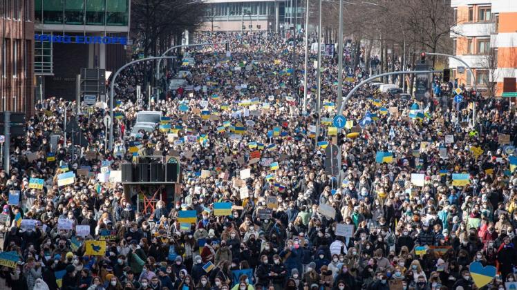 Viele tausend Demonstrierende gehen über die Willy-Brandt-Straße, eine Hauptverkehrsstraße Hamburgs, dabei tragen sie Transparente und Flaggen der Ukraine.