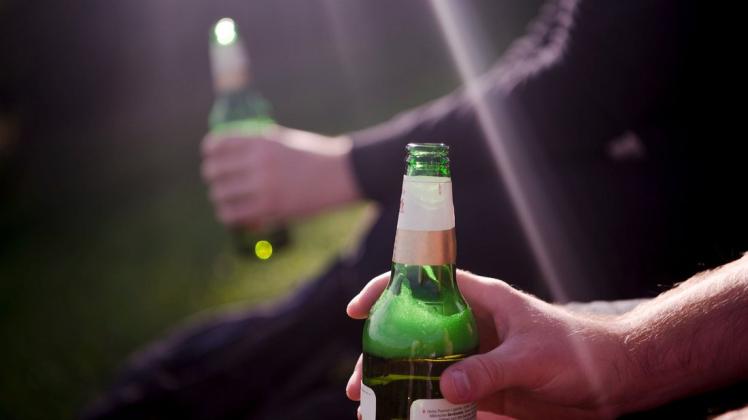 Zwei Männer sitzen in einem Park und trinken Bier.