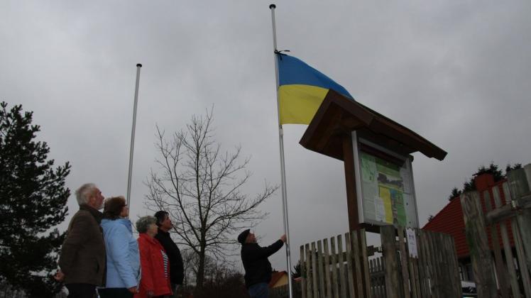 Vereinsmitglieder hängen eine ukrainische Fahne auf Halbmast.