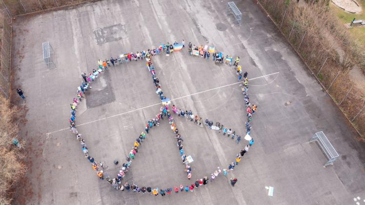 200 Grundschüler haben sich am Dienstagmorgen auf dem Schulhof der Heinrich-Schüren-Schule zu einem riesigen Peace-Zeichen formiert.