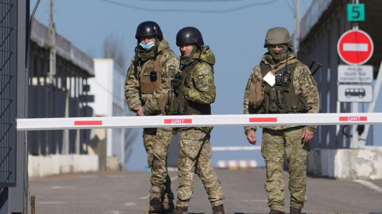 Ukrainische Grenzbeamte stehen an einem Kontrollpunkt zwischen dem von den von Russland unterstützten Separatisten kontrollierten Gebiet und dem von den ukrainischen Streitkräften kontrollierten Gebiet in der Ostukraine.