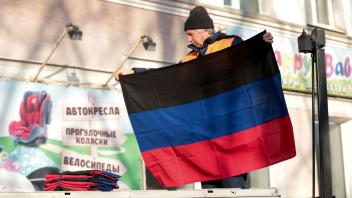 Ein Mann tauscht in Donezk eine Flagge aus.
