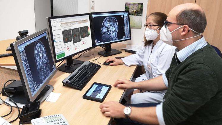 Oberärztin Dr. Annette Großmann (l.) und Informatiker Dr. Martin Dyrba mit der neuen App (mittig). KI-Methoden analysieren die MRT-Aufnahmen des Gehirns und markieren automatisch krankheitstypische Auffälligkeiten rot.