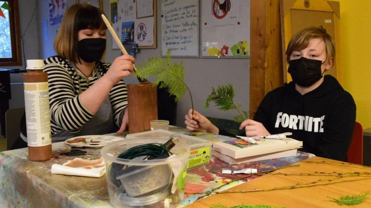 Ferienkind Julien lernt bei Erzieherin Sarah Flauder vom Schweriner Jugendtreff Wüstenschiff, wie man Meisenknödel und Vogelhäuschen aus Tetrapacks herstellt.