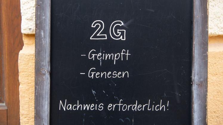 Ein Schild mit der Aufschrift "2G - Geimpft - Genesen - Nachweis erforderlich" steht vor einem Wirtshaus.