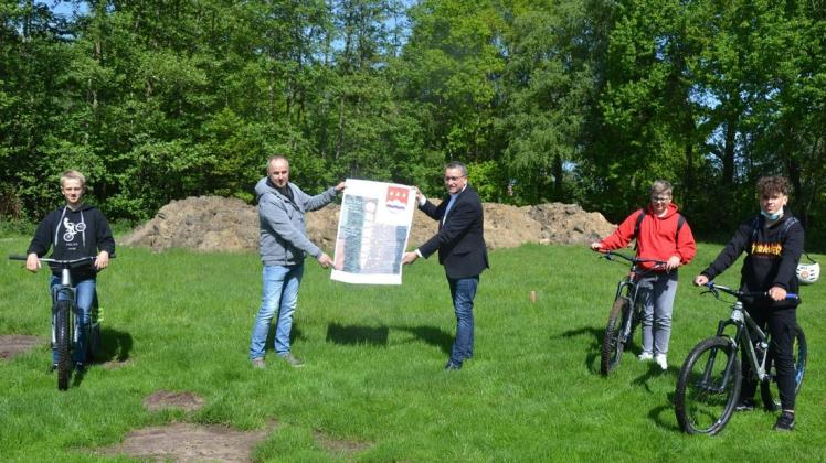 Das Projekt Bikepark steht kurz vor der Umsetzung. Darüber freuen sich die Jugendlichen Felix Bertels, Bennet Kaiser und Leo Beernink (mit Fahrrädern, von links) ebenso wie Rainer Wessels-Tappe vom Bauamt und Bürgermeister Andreas Kaiser.