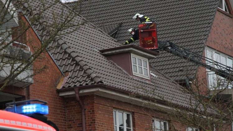 Feuerwehrleute inspizieren auf der Drehleiter das Dach der Sparkassen-Filiale in der Rathausstraße in Bargteheide.