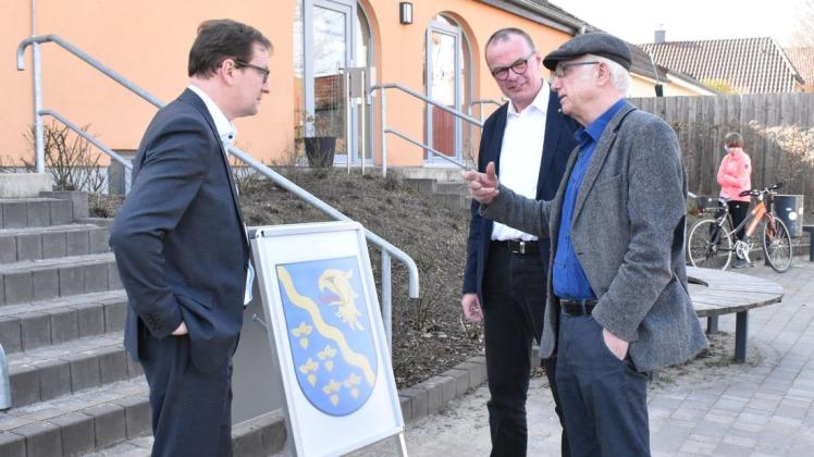Manfred Gerth (r.) erklärt Innenminister Torsten Renz (l.) und Bürgermeister Jürgen Ahrens vor dem Mehrgenerationenhaus in Papendorf, "wie die Rüben auf das Wappen" kamen.
