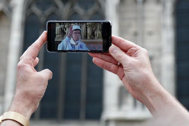 Vor der Kathedrale verfolgten mehrere Menschen die Messe in einem Livestream. Foto: AFP/ZAKARIA ABDELKAFI