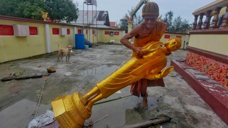In Thailand haben die Aufräumarbeiten begonnen: Ein buddhistischer Mönch richtet nach dem Tropensturm "Pabuk" eine Buddha-Statue auf. Foto: dpa/Sumeth Panpetch