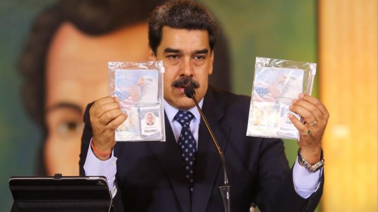 Venezuelas Präsident Nicolas Maduro hält die Ausweise zweier angeblicher US-Bürger in der Hand, denen die venezolanische Regierung der Mitwirkung bei einem Invasionsversuch bezichtigt.