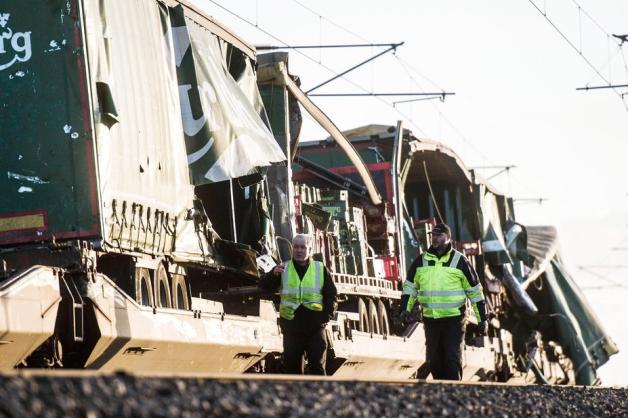 Zwei Männer in Warnwesten gehen vor einem beschädigten Güterzug, nahe der Brücke über den Großen Belt bei Nyborg. Foto: dpa/Tim K. Jensen