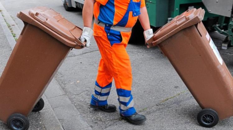 Ein Müllwerker schiebt eine braune Tonne zur Leerung. In vielen Straßen des Landkreises müssen Bürger künftig ihre Tonne selbst zu einem Sammelplatz bringen, damit sie dort von der Müllabfuhr geleert werden. Symbolfoto: Patrick Seeger/dpa