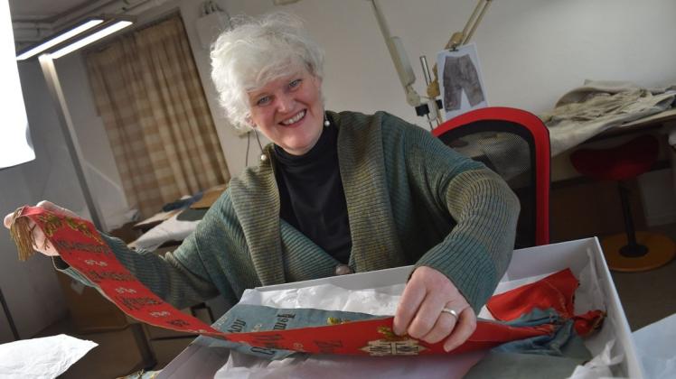 Textilrestauratorin Susanne Buch aus Diedrichshagen soll für das Heimatmuseum Warnemünde den Aufwand für das Restaurieren dieser Fahnenschleifen und noch von drei Fahnen einschätzen.