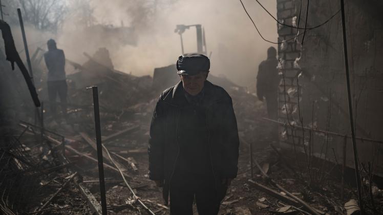 Ein Mann steht inmitten des Rauchs eines brennenden Hauses, das nach einem russischen Angriff in Charkiw zerstört wurde. Vor dem Krieg in der Ukraine fliehen Millionen von Menschen. Auch ins Emsland. Dieses Foto entstand in Charkiw.