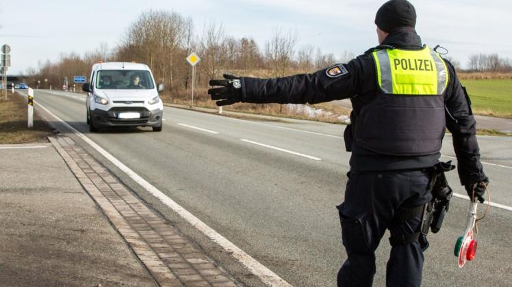 Ein Polizist winkt einen Autofahrer nach einer Geschwindigkeitsmessung an den Straßenrand.