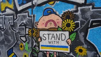 „Stand with Ukraine“ - stehe auf der Seite der Ukraine. Eine klare Botschaft an einer Wand in der lettischen Hauptstadt Riga, die mit Graffiti bemalt wurde.