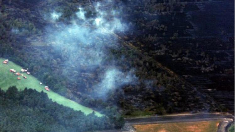 Ein Luftbild aus einem Tornado der Bundeswehr zeigt die östliche Moorkante aus Blickrichtung West/Ost. Auf einer Wiese stehen Fahrzeuge der Feuerwehr, über dem Wald hängen Wolken. Foto: Luftwaffe/Bundeswehr/dpa