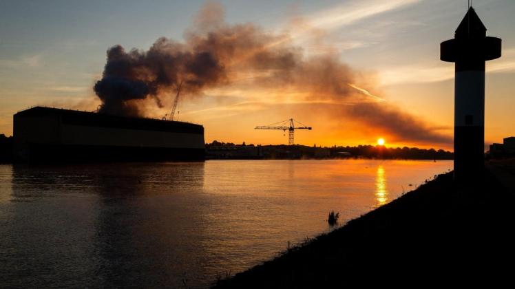 Rauch steigt über der Lürssen-Werft in Bremen-Vegesack in den Himmel. In der Werft war in der Nacht zum Freitag ein Dock zum Bau von Schiffen samt Schiffsneubau in Flammen aufgegangen. Foto: Mohssen Assanimoghaddam/dpa