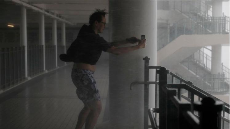 Ein Mann in Hongkong fotografiert, während um ihn herum am Victoria Habour der Sturm tobt. Foto: Vincent Yu/AP/dpa
