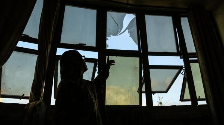 Eine palästinensische Frau inspiziert ein bei einem Luftangriff zerstörtes Fenster. Nach palästinensischen Angriffen mit Branddrachen hat die israelische Luftwaffe Ziele im Gazastreifen bombardiert. Foto: dpa/Dawoud Abo Alkas/APA Images via ZUMA Wire