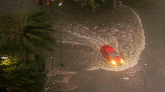Ein Auto fährt während heftiger Regenfälle und starken Winden über eine überflutete Straße. Foto: dpa/Bullit Marquez