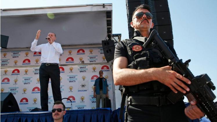 Der türkische Präsident Recep Tayyip Erdogan wird während seiner Rede bei einer Wahlkampfveranstaltung von einem bewaffneten Polizisten bewacht. Foto: dpa/Lefteris Pitarakis