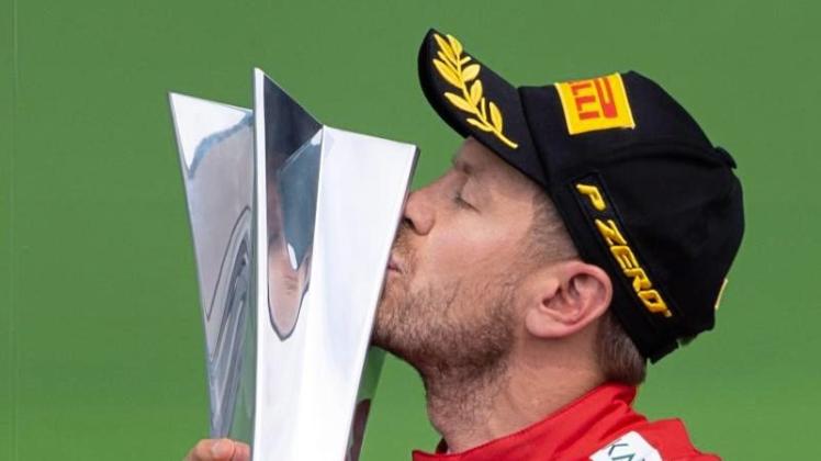 Sebastian Vettel küsst auf dem Podium in Montréal seine Siegestrophäe. 