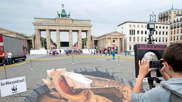 Mit dem 3D-Bild eines Braunkohletagebaus protestieren Umweltschützer in Berlin für eine Veränderung der Umweltpolitik. Kanzlerin Merkel spricht beim „Petersberger Klimadialog“. 