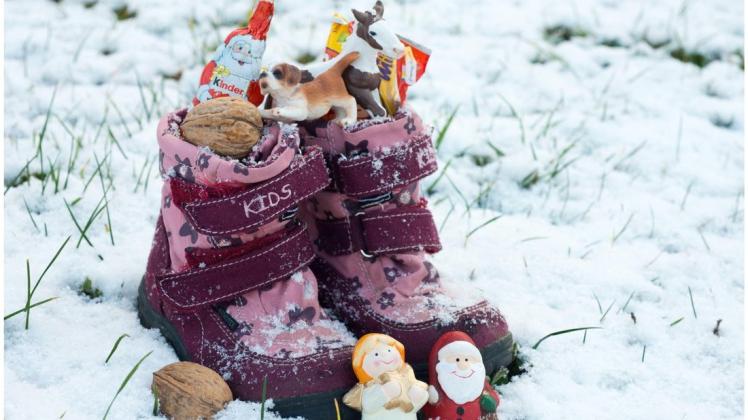 Idealbild eines Nikolaustags: Erster Schnee und mit Süßigkeiten und Nüssen gefüllte Kinderschuhe. Foto: Patrick Pleul/dpa