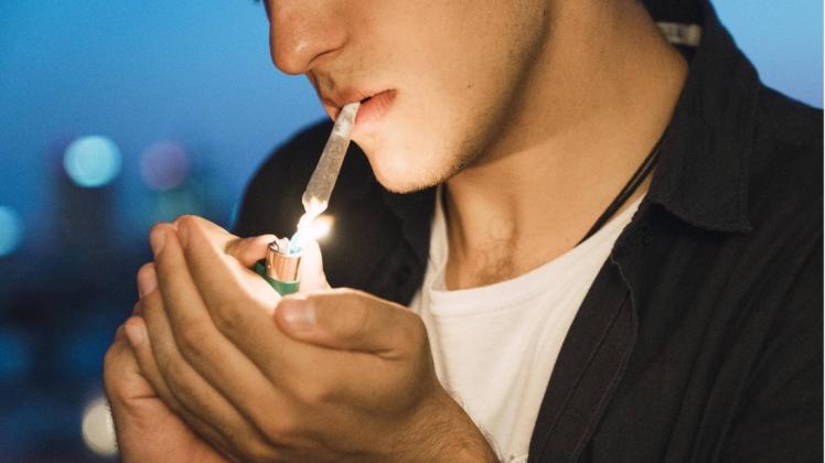 Ein junger Mann steckt sich einen Joint an. Ist das auch in Deutschland bald legal möglich? Foto: imago/Kike Arnaiz