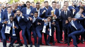 Präsident Emmanuel Macron (Fünfter von rechts) empfängt die Weltmeister: In Paris feierten Franzosen den Erfolg ihrer Mannschaft frenetisch. Foto: dpa/Francois Mori/AP