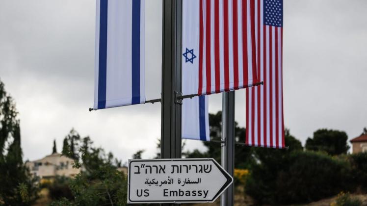Eine Israelische und US-amerikanische Flagge sind über einem Schild angebracht, das den Weg zur Botschaft der USA weist. Die US-Botschaft wird ab dem 14. Mai vorübergehend im Gebäude des US-Konsulats untergebracht. Foto: dpa