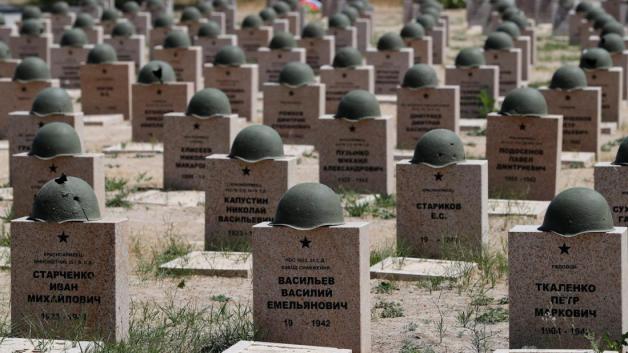 Stahlhelme liegen auf den Grabsteinen auf dem „Soldatenfriedhof Rossoschka“. Hier liegen gefallene Soldaten der deutschen Wehrmacht und der Roten Armee, nur getrennt durch eine schmale Straße. Foto: dpa