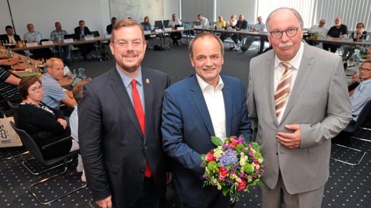 Mit Blumen gratulierten Bürgermeister Jan Peter Bechtluft (links) und Ratsvorsitzender Friedhelm Führs (rechts) dem neuen Ersten Stadtrat und Kämmerer Hermann Wessels. 
