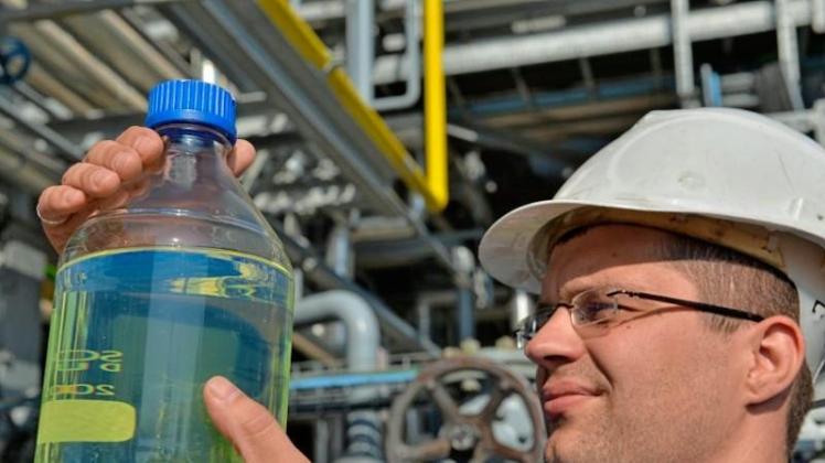 Ein Ingenieur von der TU Bergakademie Freiberg hält eine Flasche mit synthetisch hergestelltem Benzin in den Händen. 