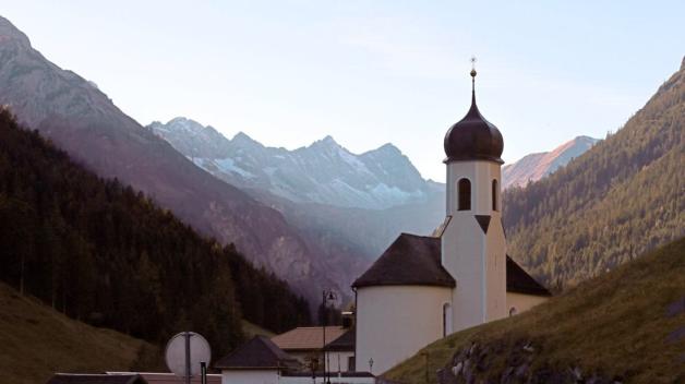 Die Pfarrkirche des Ortes im Lechtal - im Hintergrund sind die Alpen zu sehen. Wissenschaftler gehen davon aus, dass der Gipfel des Hochvogels an der Grenze zwischen Bayern und Österreich bald auseinanderbricht und bis zu 260 000 Kubikmeter Fels ins Tal stürzen werden. 