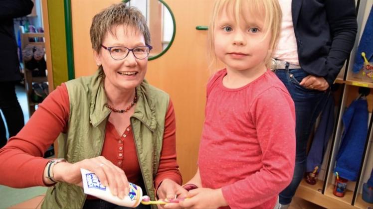 Edith Ohlenbusch, Leiterin der Kindertagesstätte „Sonneninsel“ in Bookholzberg, verteilt Zahnpasta auf die Bürste der vierjährigen Enna. 