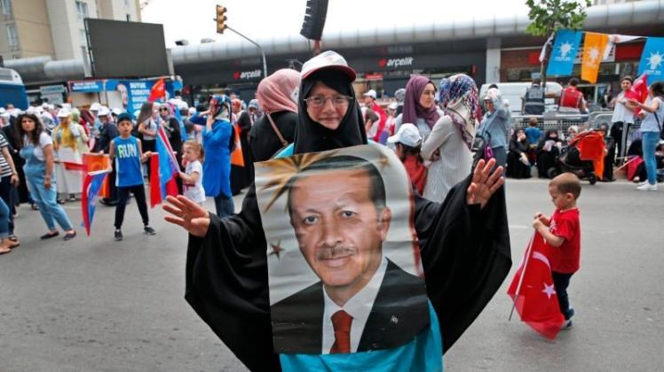 Eine Unterstützerin des türkischen Präsidenten Erdogan trägt sein Konterfei bei einer Wahlkampfveranstaltung der Regierungspartei AKP. 