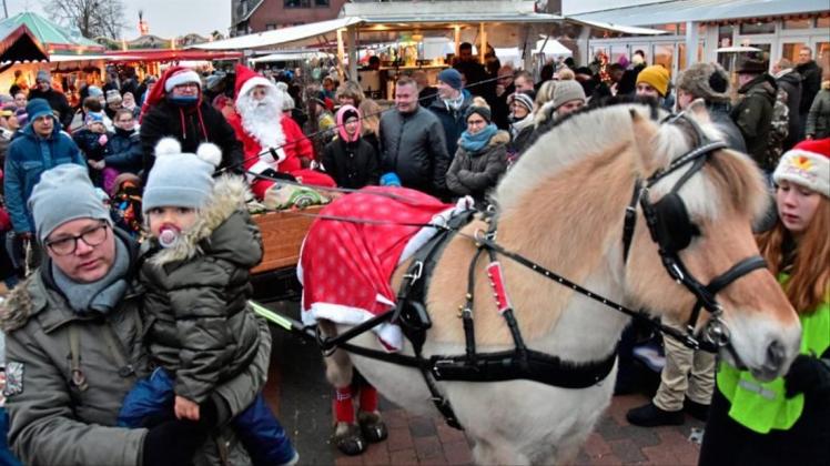 Auf dem Weg zur Bescherung: Der Weihnachtsmann bahnt sich in seiner Kutsche einen Weg durch die Menge der schaulustigen Marktbesucher. 