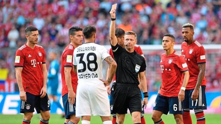 Schiedsrichter Tobias Welz (M) zeigt die Rote Karte gegen den Leverkusener Karim Bellarabi (38) für das Foul an Rafinha. Foto: Tobias Hase Schiedsrichter Tobias Welz (M) zeigt die Rote Karte gegen den Leverkusener Karim Bellarabi (38) für das Foul an Rafinha. Foto: Tobias Hase