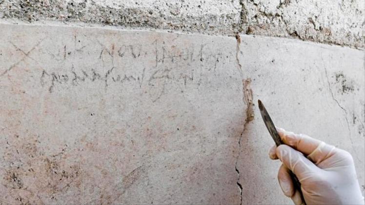 Ein Archäologe zeigt an einer Mauer in Pompeji die Kohle-Inschrift, die auf die Eruption des Vesuv im Jahr 79 verweist. 