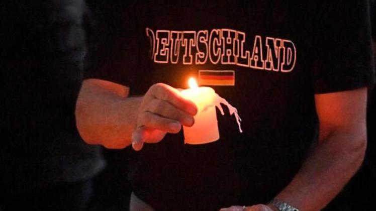 Ein Teilnehmer einer Kundgebung für den verstorbenen 22-Jährigen legt auf einem Spielplatz in Köthen eine Kerze ab. 