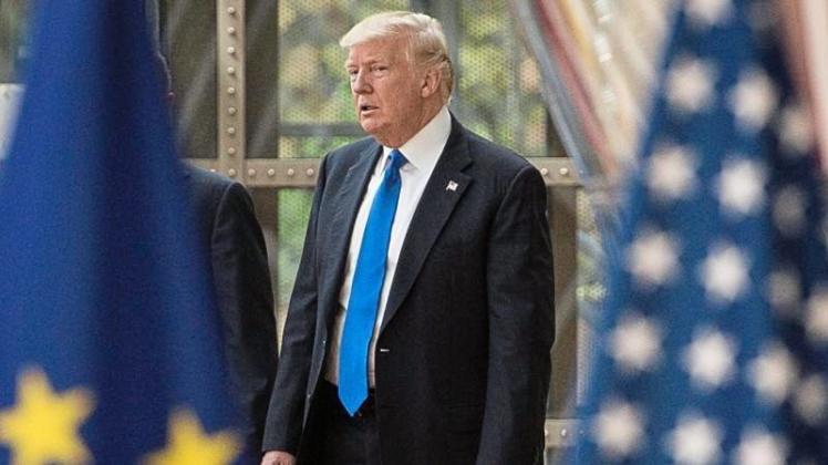 US-Präsident Trump zwischen den Fahnen der EU und der USA. 