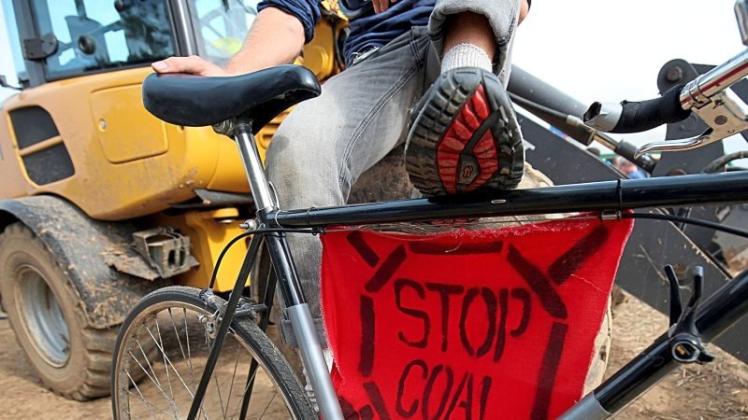 Ein Aktivist sitzt im Klima Camp auf einem Fahrrad, an dem ein Transparent mit dem Schriftzug „Stop Coal“ festgebunden ist. Zum Auftakt der angekündigten Protest-Tage von Braunkohle-Gegnern hat es noch keine Aktionen gegeben. 