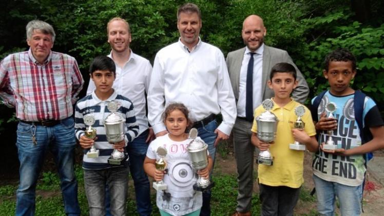 Jugendhaus-Leiter Jörg Mehrens (links) und die Sponsoren vom Round Table 91 Delmenhorst haben die Pokale an die besten Nachwuchs-Minigolfer (vorne von links) Roda, Alysa, Yusuf und Jermaine überreicht. 
