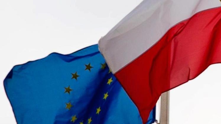 Eine EU-Flagge weht neben einer polnischen Flagge. Die EU-Kommission hat ein Vertragsverletzungsverfahren gegen Polen eingeleitet. 
