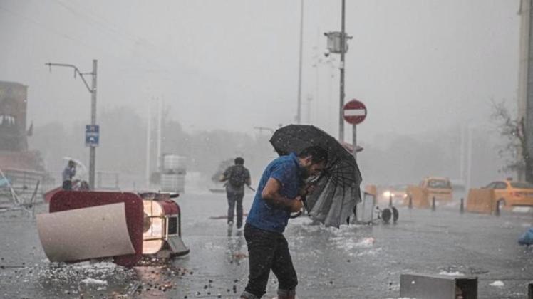 Passanten kämpfen sich bei heftigem Regen über den Taksim-Platz. 