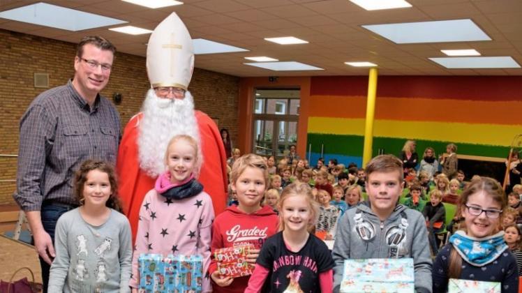 Viele Pakete hatte der Nikolaus für jede Klasse der Waldschule in Leschede mitgebracht. Rektor Jens Boermann (links) unterstützte den Nikolaus beim Verteilen der Geschenke an die Klassenvertreter. 